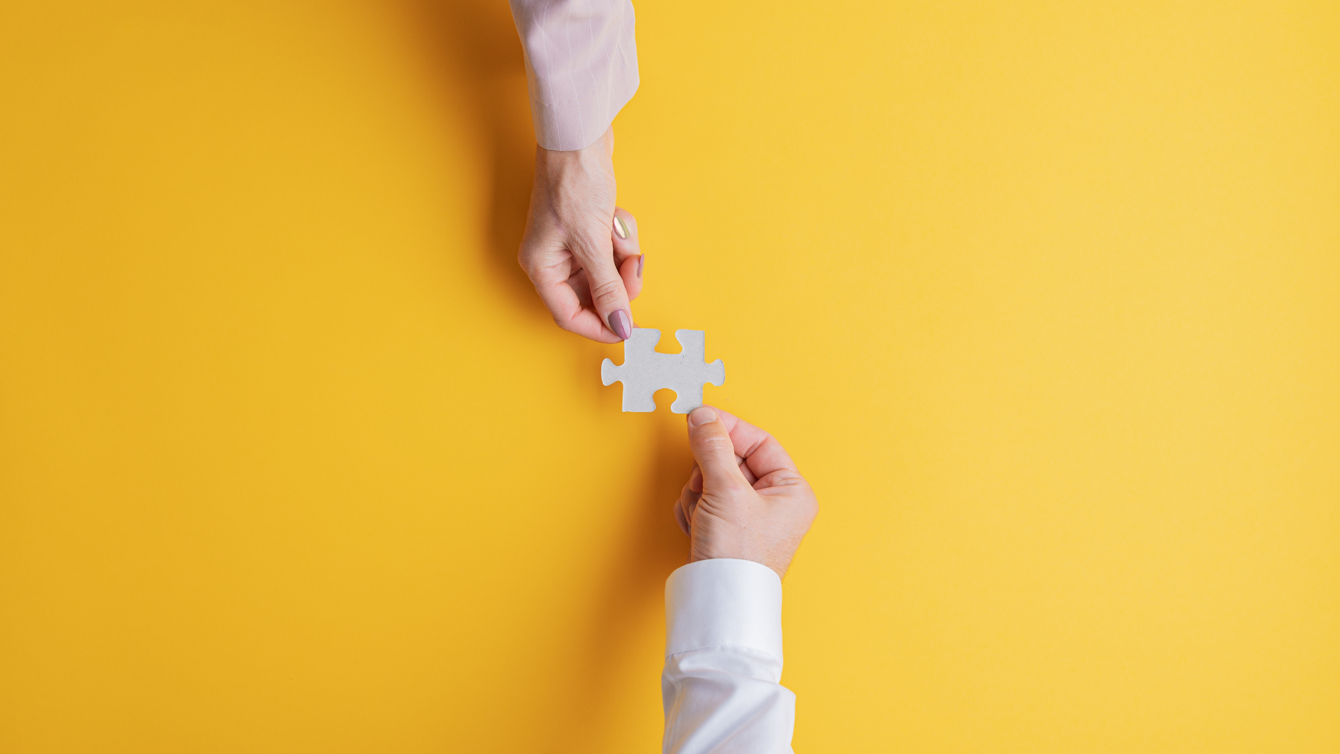 Two people holding a jigsaw piece
